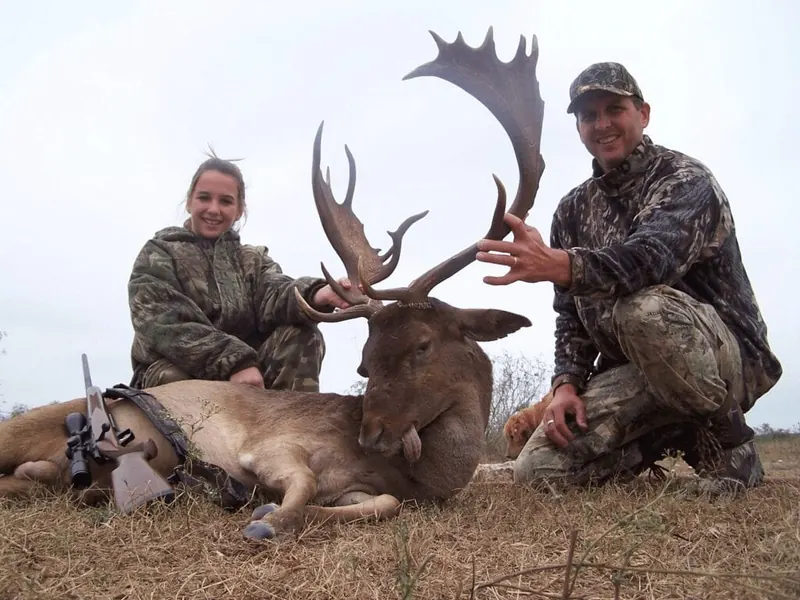 Two hunters with a fallow deer buck